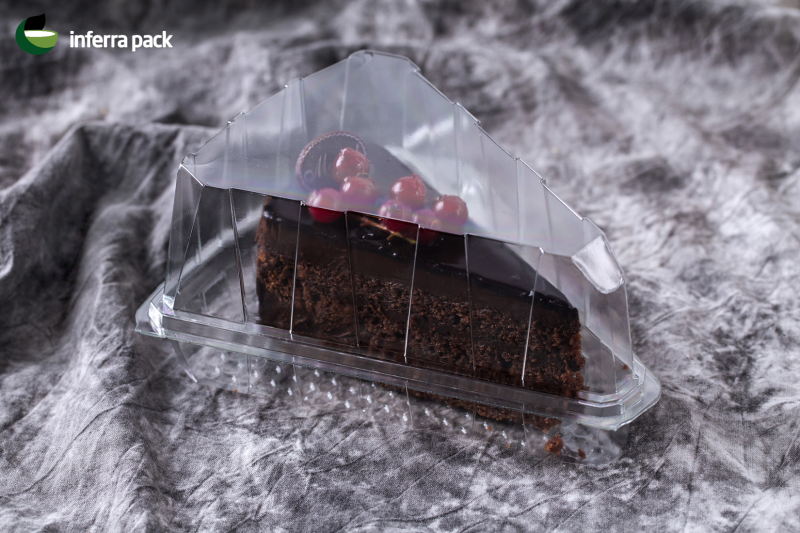 Disposable triangle cake slice container with clear base and clear lid.